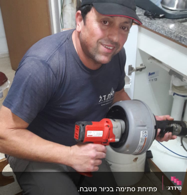 אדם מחזיק מכשיר אינסטלציה מתחת לכיור במטבח